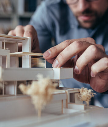 Close,Up,Of,Male,Architect,Hands,Making,Model,House.,Man
